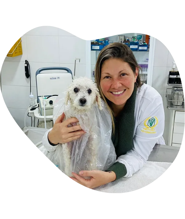 Dra. Laiza Cassia sorrindo com um poodle branco envolto na bolsa de ozonioterapia